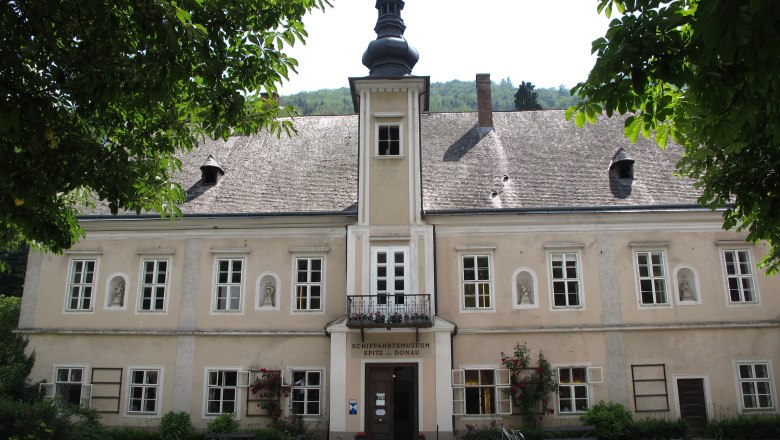 Außenansicht Schifffahrtsmuseum, © Birgit Fischer Außenansicht eines historischen Gebäudes mit Schindeldach und Turm, umgeben von Bäumen.
