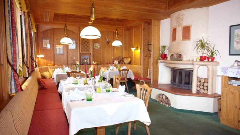 Gemütlicher Raum mit Holzwänden, gedeckten Tischen und Kamin.