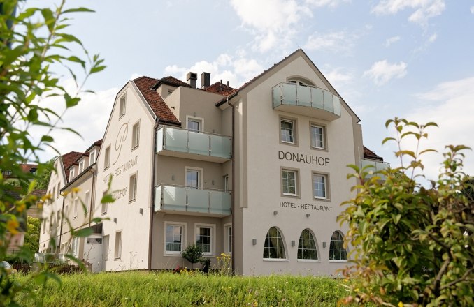 Au&szlig;enansicht des Hotel Restaurant Donauhof mit Balkonen und Garten.