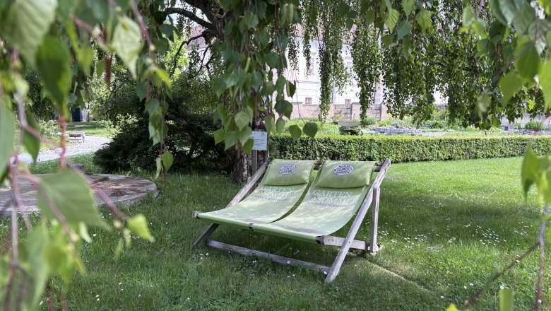 Zwei gr&uuml;ne Liegest&uuml;hle im Garten des Stift Geras unter einem Baum.