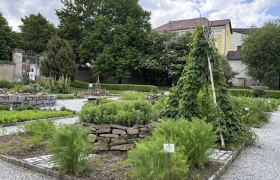 Heilkr&auml;utergarten im Stift Geras mit verschiedenen Pflanzenbeeten und einem Rankger&uuml;st aus Holz.