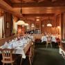 Gem&uuml;tliches Restaurant mit Holzw&auml;nden, gedeckten Tischen und Kamin.