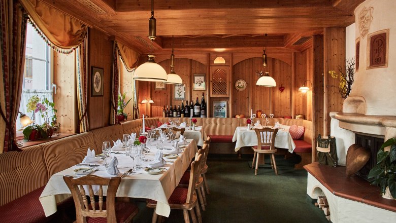 Gem&uuml;tliches Restaurant mit Holzw&auml;nden, gedeckten Tischen und Kamin.