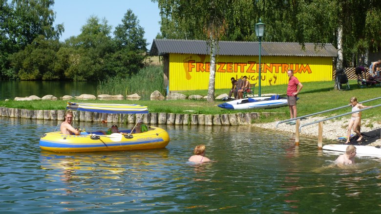 Menschen genie&szlig;en einen sonnigen Tag am See im Freizeitzentrum Langau.