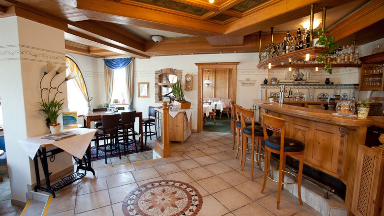 Gem&uuml;tliche Hotelbar mit Holzm&ouml;beln und dekorativem Fliesenboden.